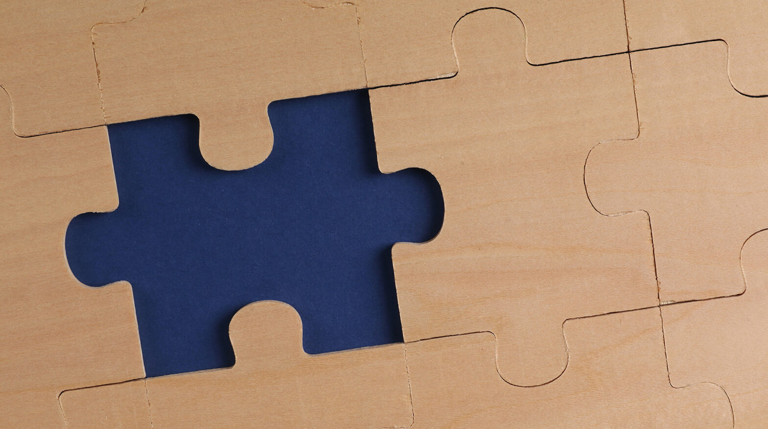 wooden puzzle with one missing piece with blue background